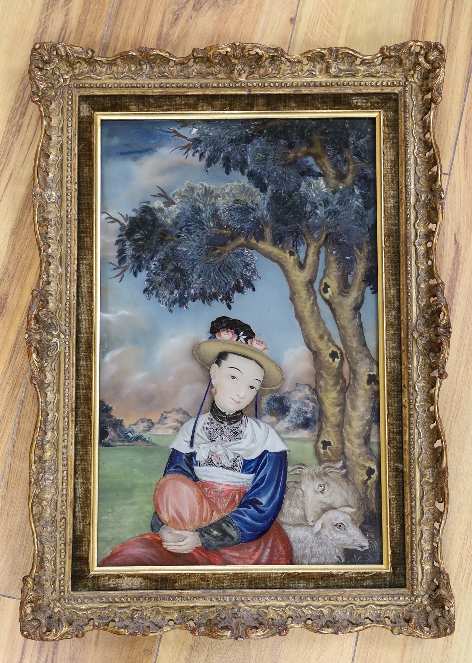 A mid 19th century Chinese reverse painting on glass, depicting a figure and goats seated beneath a tree, 38 x 23cm